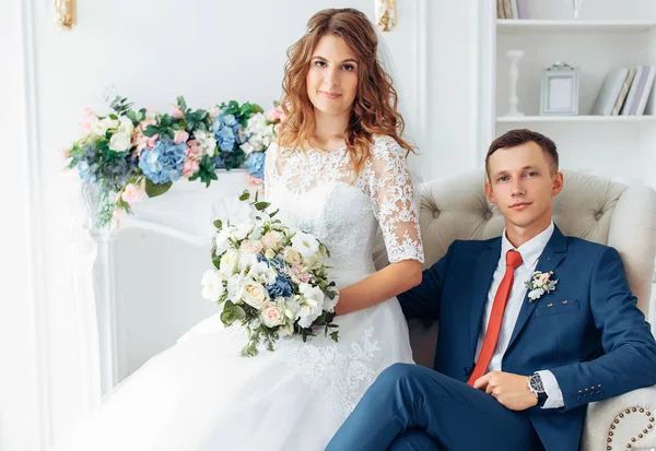Bela noiva em vestido branco e noivo em terno, posando em interior estúdio branco, casamento — Fotografia de Stock