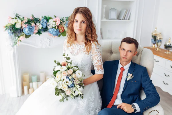 Vacker brud i vit klänning och brudgummen i kostym, poserar i vit Studio inredning, bröllop — Stockfoto