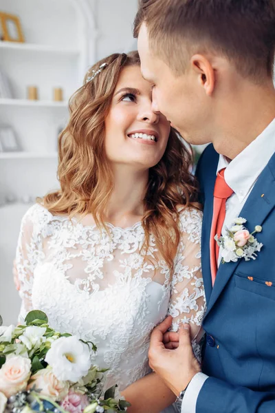 Hermosa novia en vestido blanco y novio en traje, posando en el interior del estudio blanco, boda —  Fotos de Stock