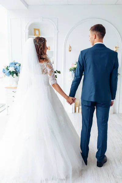 Bela noiva em vestido branco e noivo em terno, posando em interior estúdio branco, casamento — Fotografia de Stock