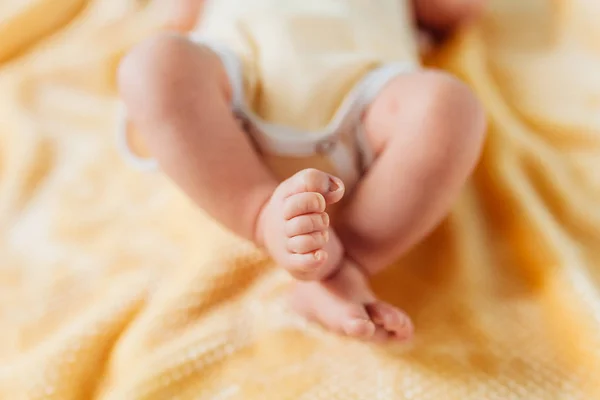 Pasgeboren baby, benen close-up, liggend op een zachte deken — Stockfoto