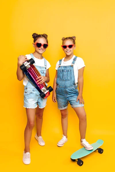 Dos adolescentes, niños elegantes posando con patinetas en su —  Fotos de Stock