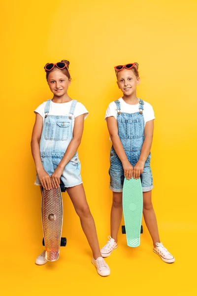 Dos adolescentes, niños elegantes posando con patinetas en su —  Fotos de Stock
