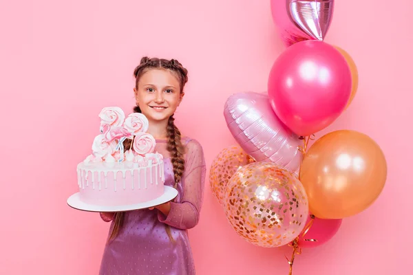 Una adolescente con globos sostiene un pastel en sus manos, en un alfiler — Foto de Stock