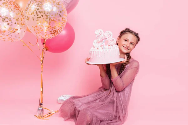 Una adolescente con globos sostiene un pastel en sus manos, en un alfiler — Foto de Stock