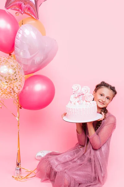 Una adolescente con globos sostiene un pastel en sus manos, en un alfiler — Foto de Stock