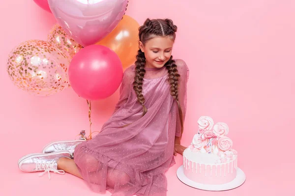 Adolescente con globos y un pastel de cumpleaños posando en un rosa — Foto de Stock