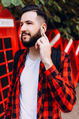 kablosuz kulaklık ile sakallı adam, hipster şehirde yürürken iletişim kurar.