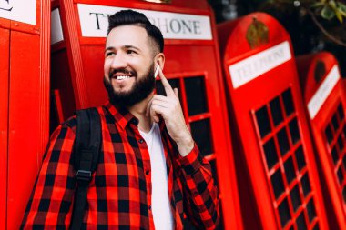 Kablosuz kulaklık ile sakallı şık adam, hipster şehirde mobil iletişim kurar