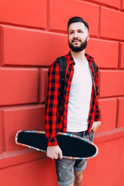 bir kaykay ile bir tuğla boş duvar bir arka plan üzerinde sakallı adam