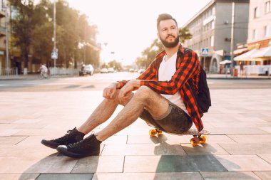 gün batımında kaykay ile sakallı adam.