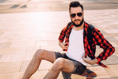 gün batımında kaykay ile sakallı adam.