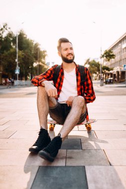 gün batımında kaykay ile sakallı adam.