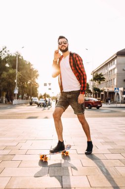 kablosuz kulaklık bir sakallı adam şehir etrafında bir kaykay sürme