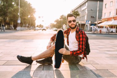 kablosuz kulaklık bir sakallı adam bir kaykay ile bir parkta oturur