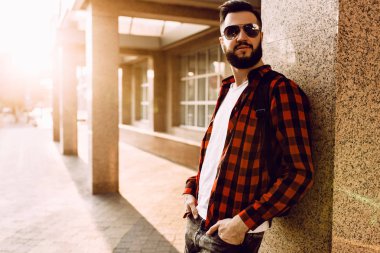 Kablosuz kulaklık sakallı şık adam şehirde bir binanın yakınında poz