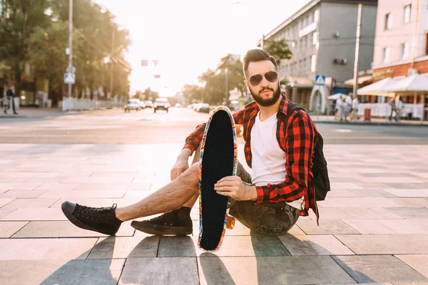 kablosuz kulaklık bir sakallı adam bir kaykay ile bir parkta oturur