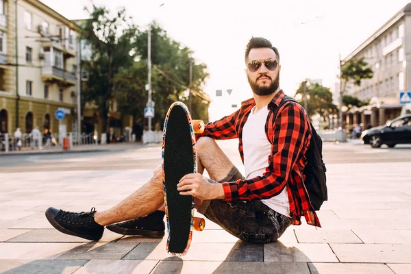 kablosuz kulaklık bir sakallı adam bir kaykay ile bir parkta oturur