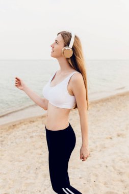 güzel atletik kız denizde yürüyüş ve musi dinlerken