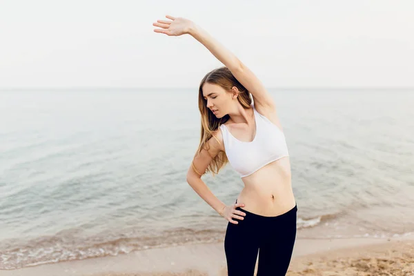 Schöne junge Sport-Fitness-Frau im Freien am Strand in th — Stockfoto