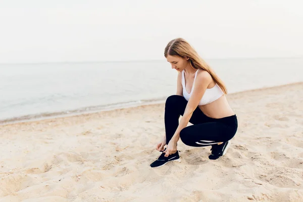 Junges sportliches Mädchen, das Schnürsenkel an Sportschuhen bindet, — Stockfoto