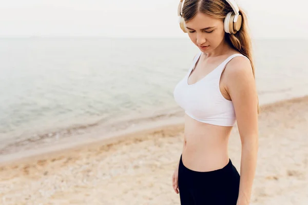 Mooie atletische meisje wandelen op de zee en luisteren naar Musi — Stockfoto