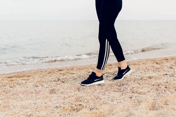 穿着运动鞋在沙滩上行走的脚的特写图像 — 图库照片