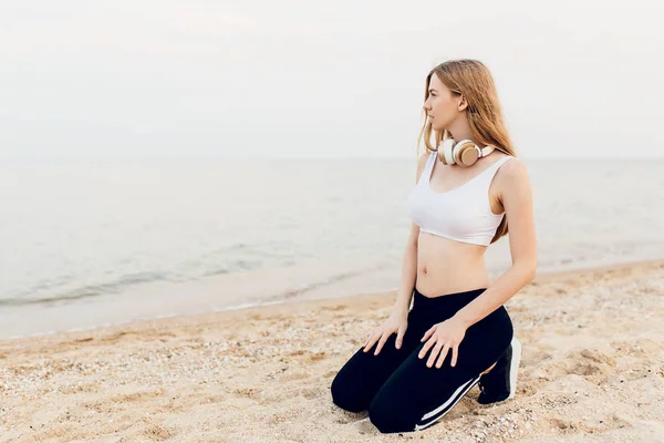 Jong meisje in Sportswear in de ochtend buitenshuis op het strand, d — Stockfoto