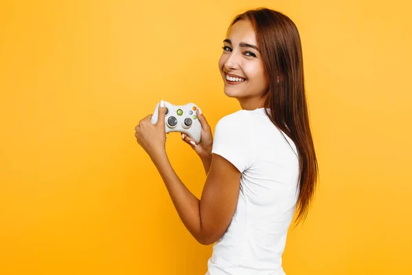 Een vrouw glimlacht naar de camera en houdt een joystick in haar hand, o — Stockfoto