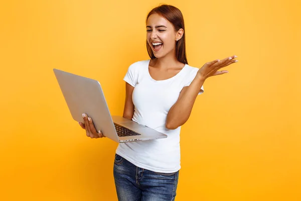 Retrato de la joven excitada sosteniendo el ordenador portátil y celebrando su —  Fotos de Stock