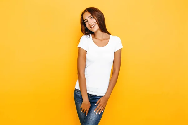 Jovem mulher bonita em uma camiseta branca posando em um fundo amarelo — Fotografia de Stock