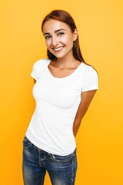 Jovem mulher bonita em uma camiseta branca posando em um fundo amarelo — Fotografia de Stock