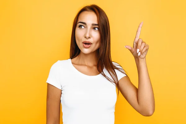 Ragazza in una t-shirt bianca, è venuto con una grande idea, su un giallo — Foto Stock