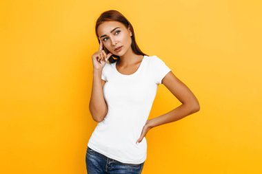 Ciddi düşünceli genç kadın sarı arka plan üzerinde düşünme