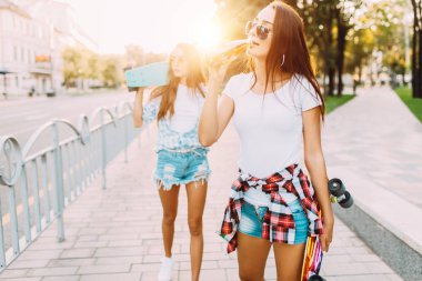 Güneş gözlüğü iki kız, bir içki içmek ve bir cit aşağı yürümek