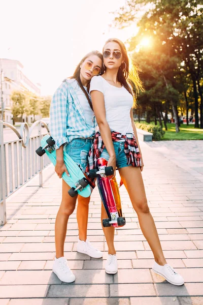 Twee vrolijke jonge meisjes in korte broek, vrienden vormen staande met s — Stockfoto