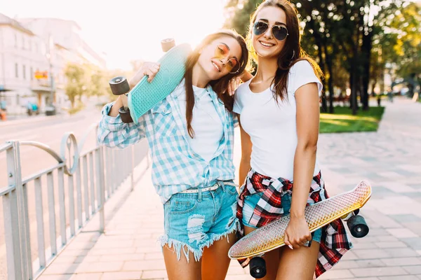 Twee vrolijke jonge meisjes in korte broek, vrienden vormen staande met — Stockfoto