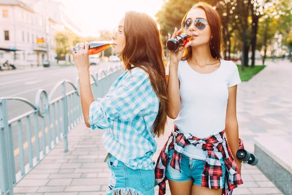 Две девушки в солнечных очках, выпьют и прогуляются по городу. — стоковое фото