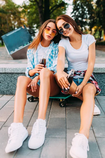 Twee meisjes in Casual kleding en zonnebrillen zitten in het Park o — Stockfoto