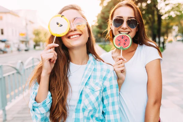 Giovani ragazze divertenti alla moda con lecca-lecca si divertono in città in — Foto Stock