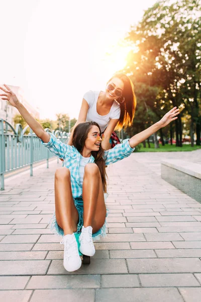 Twee stijlvolle opgewonden meiden hebben plezier en skateboard in het Park in — Stockfoto