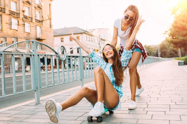 Dos chicas emocionadas con estilo se divierten y monopatín en el Parque en —  Fotos de Stock