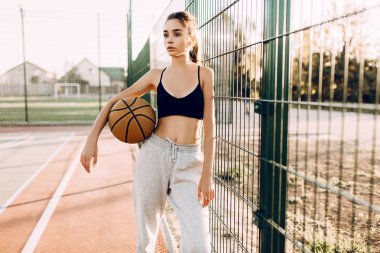 genç atletik kız, açık havada, bir basketbol ile poz. Spor, 