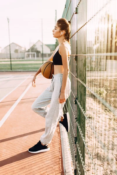 Giovane ragazza atletica, all'aperto, in posa con un pallacanestro. Sport , — Foto Stock