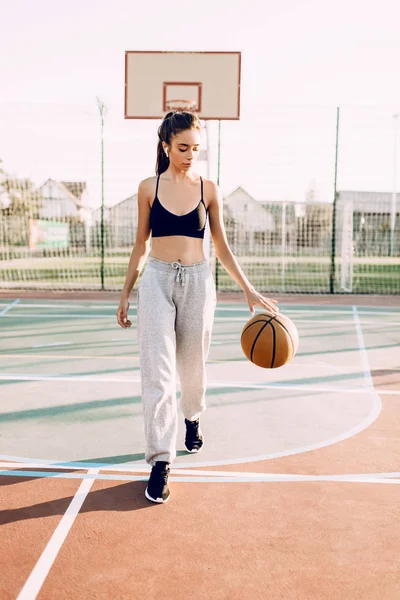 Menina bonita e desportiva brincando com a bola no basketb — Fotografia de Stock