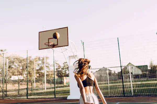 Krásná mladá atletická dívka hází míč do ringu na — Stock fotografie