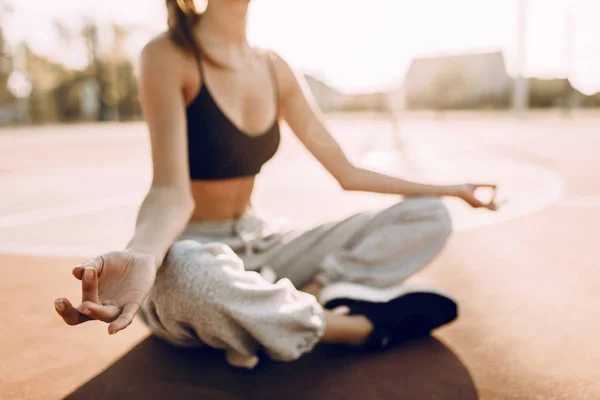 Молода жінка в спортивному одязі, сидячи на відкритому повітрі розслабляюча медитація приймає сонячні промені — стокове фото