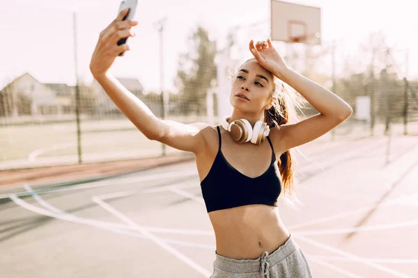 Bild einer jungen, athletischen Frau, die im Freien ein Selfie mit einem Smartphone macht — Stockfoto