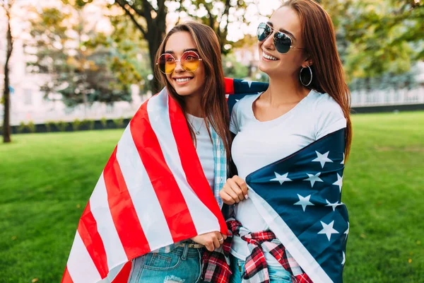 Πορτραίτο δύο όμορφων κοριτσιών που κρατούν μια αμερικάνικη σημαία εορτάζων — Φωτογραφία Αρχείου