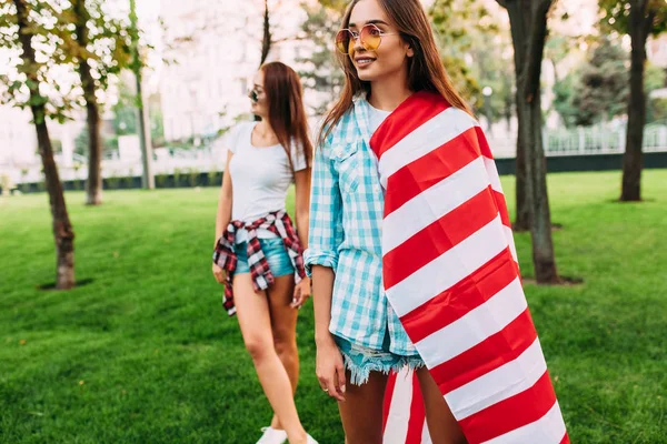 Two stylish attractive girls with an American flag, posing in th — Stock Photo, Image